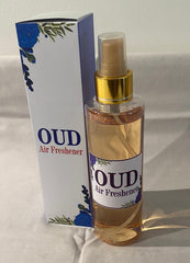 A collection of spray bottles with various home care fragrance labels, displayed on a table. The labels indicate different scent options.