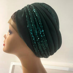 A green turban with sequins displayed on a mannequin head.