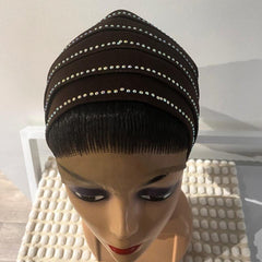A black turban with a decorative pattern displayed on a mannequin head.