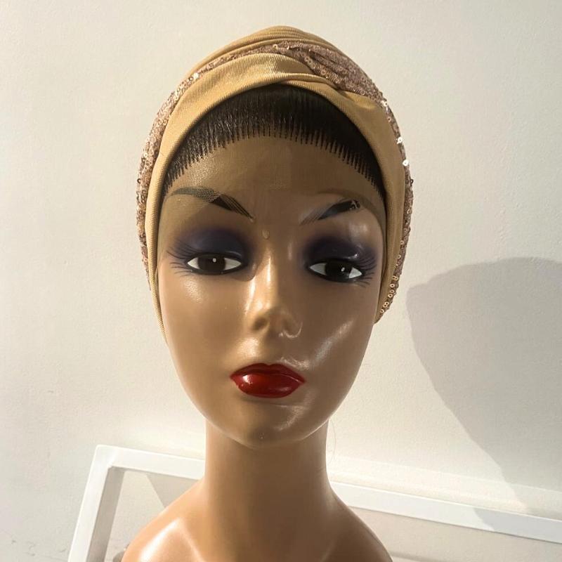 A mannequin head wearing a beige turban with a patterned design.
