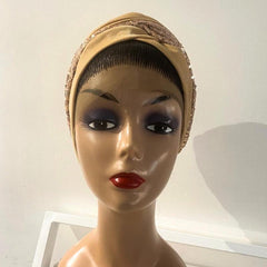 A mannequin head wearing a beige turban with a patterned design.