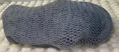A grey bath sponge with a net-like texture, placed on a light-colored surface.
