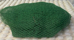 A green bath sponge with a net-like texture, placed on a light-colored surface.