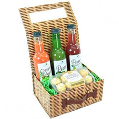 A wicker gift basket with a variety of items including bottles of sauce and condiments, and chocolate candies.