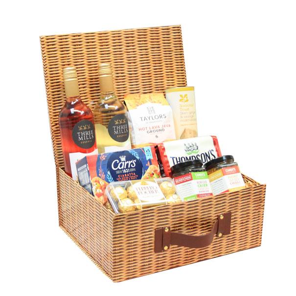 An extra large wicker hamper gift box with an assortment of food items including meats, cheeses, and crackers.