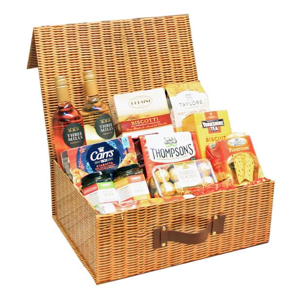 An extra large wicker hamper gift box with an assortment of food items including meats, cheeses, and crackers.