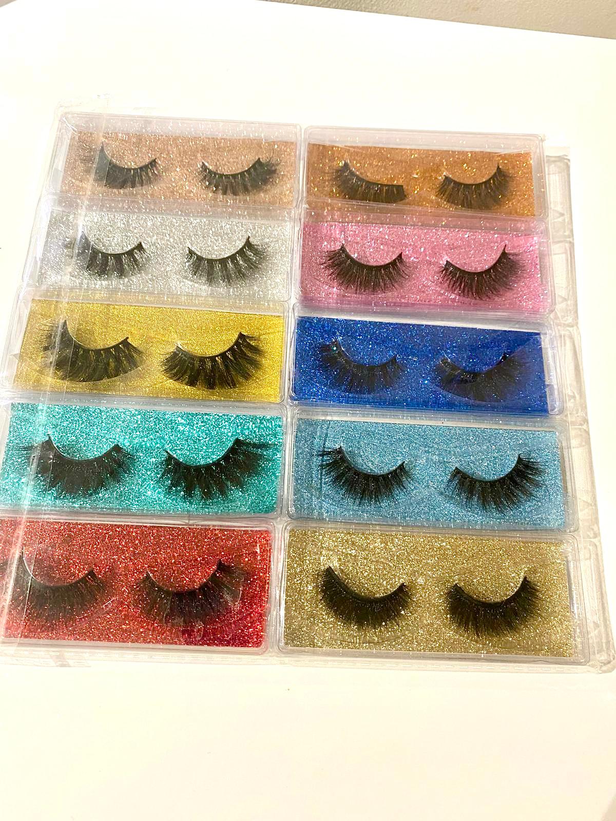 Set of false eyelashes in various colors in a clear plastic case.