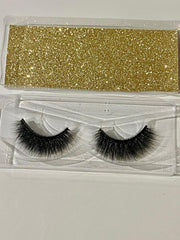 Pair of false eyelashes in a clear packaging with gold glittery top section.