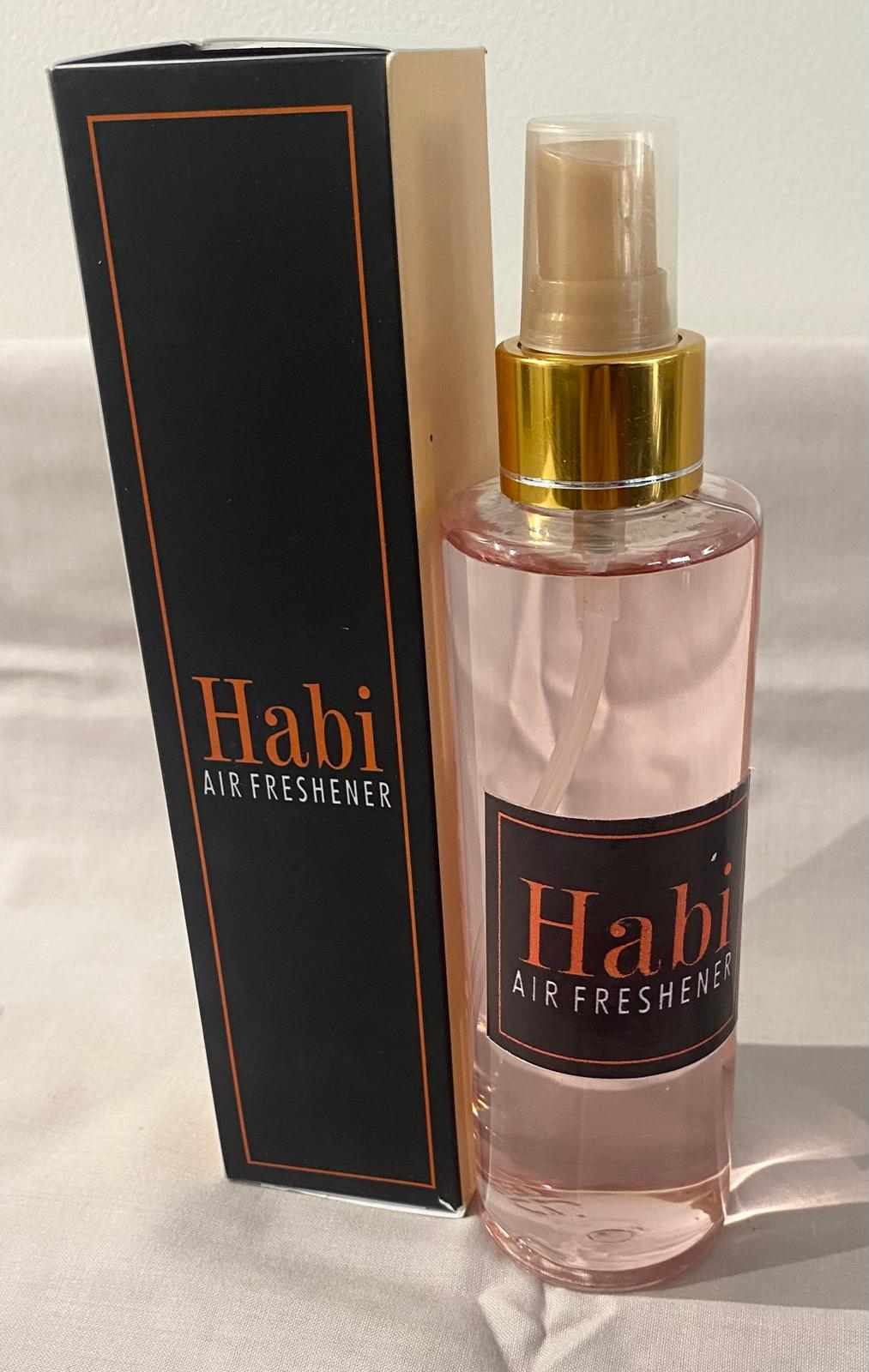 A collection of spray bottles with various home care fragrance labels, displayed on a table.