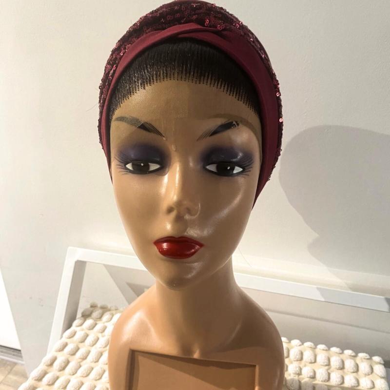 A mannequin head wearing a red turban with embellishments.