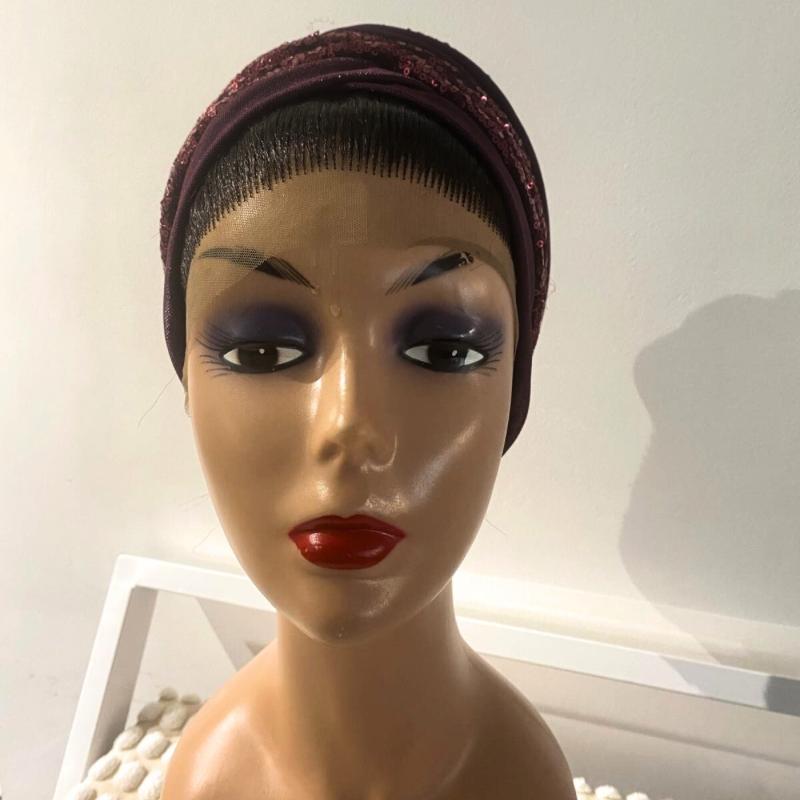 A mannequin head wearing a purple and black turban with a visible hairline.