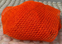 A pink bath sponge with a net-like texture, placed on a light-colored surface.