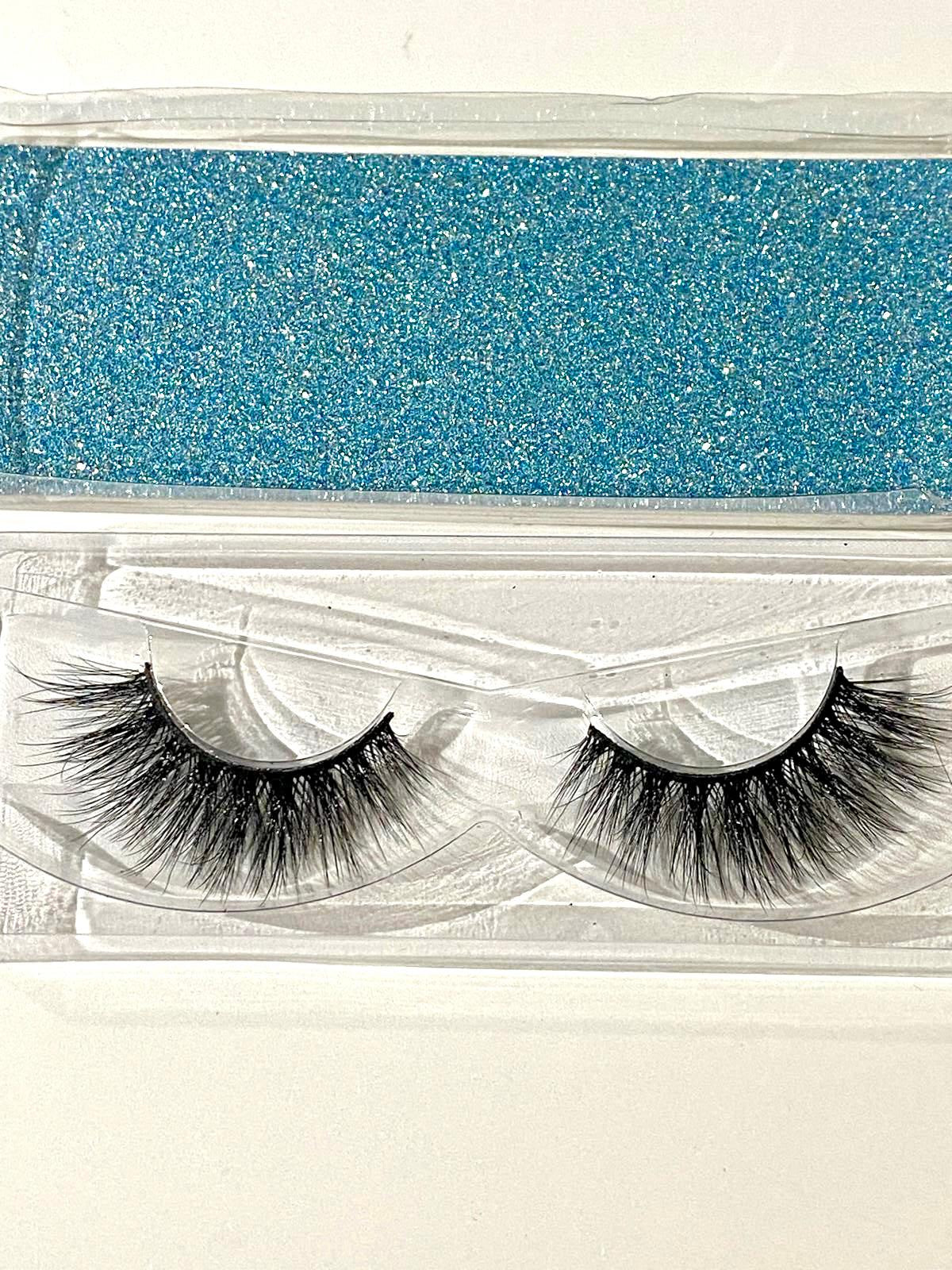 Pair of false eyelashes in a clear packaging with blue glittery background
